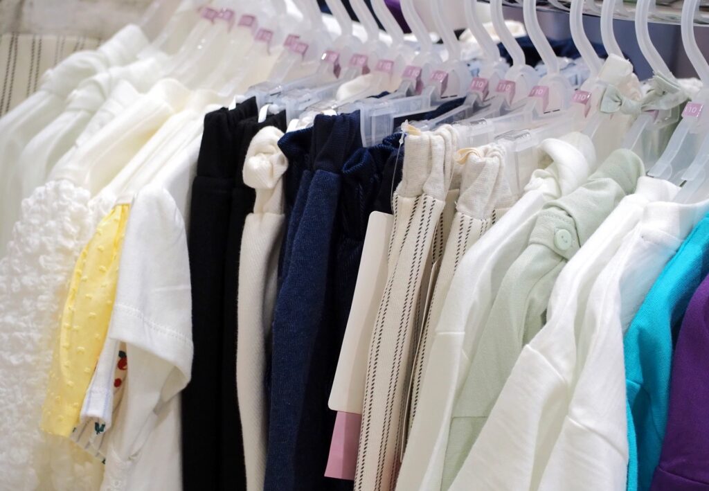 子供服リサイクルショップのハンガーに並ぶTシャツとボトムス